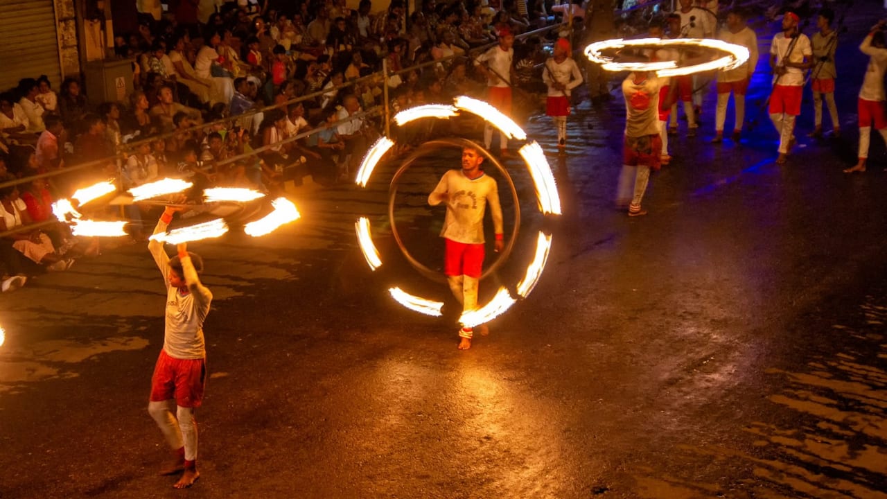 Fire dancers spinning flaming hoops during the night procession of the Kandy Esala Perahera in Sri Lanka